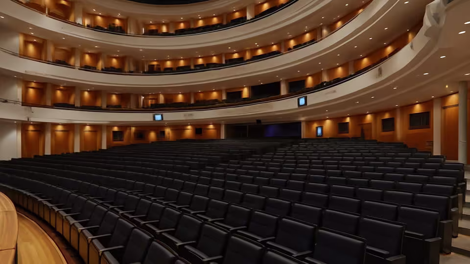 Wide-angle shot of the main hall of the Finnish National Opera in Helsinki with tiered seating and warm lighting.